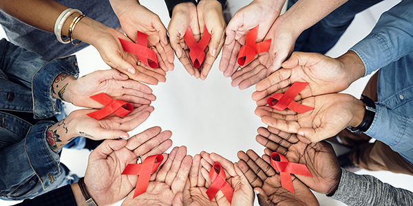 a circle of hands holding red ribbons