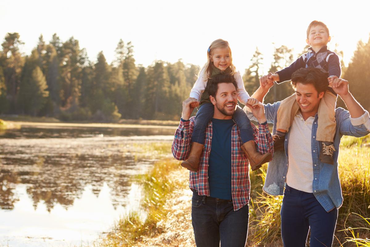 Gay male couple with children walking by a lake