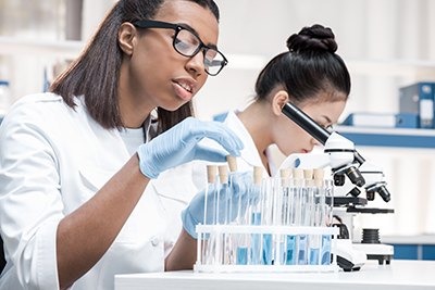 Two female scientists working with test tubes and a microscope